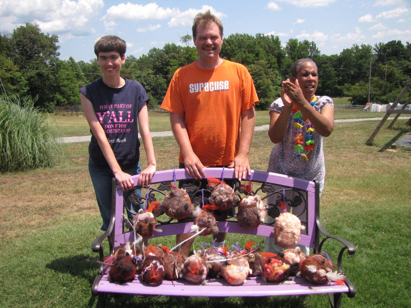 Group smiling outdoors with unique sculptures.