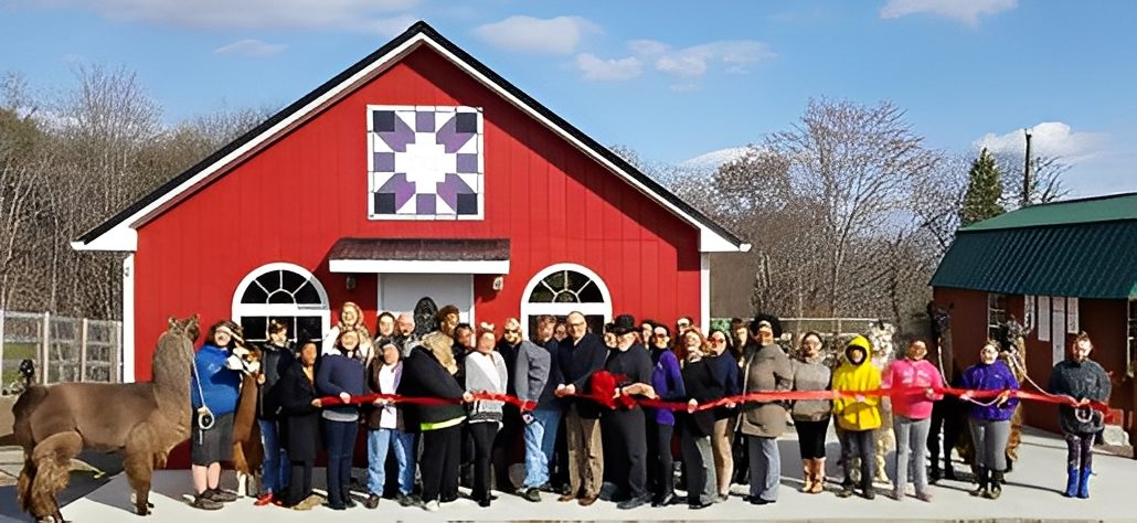 Community ribbon-cutting ceremony in front of a red building on a sunny day.