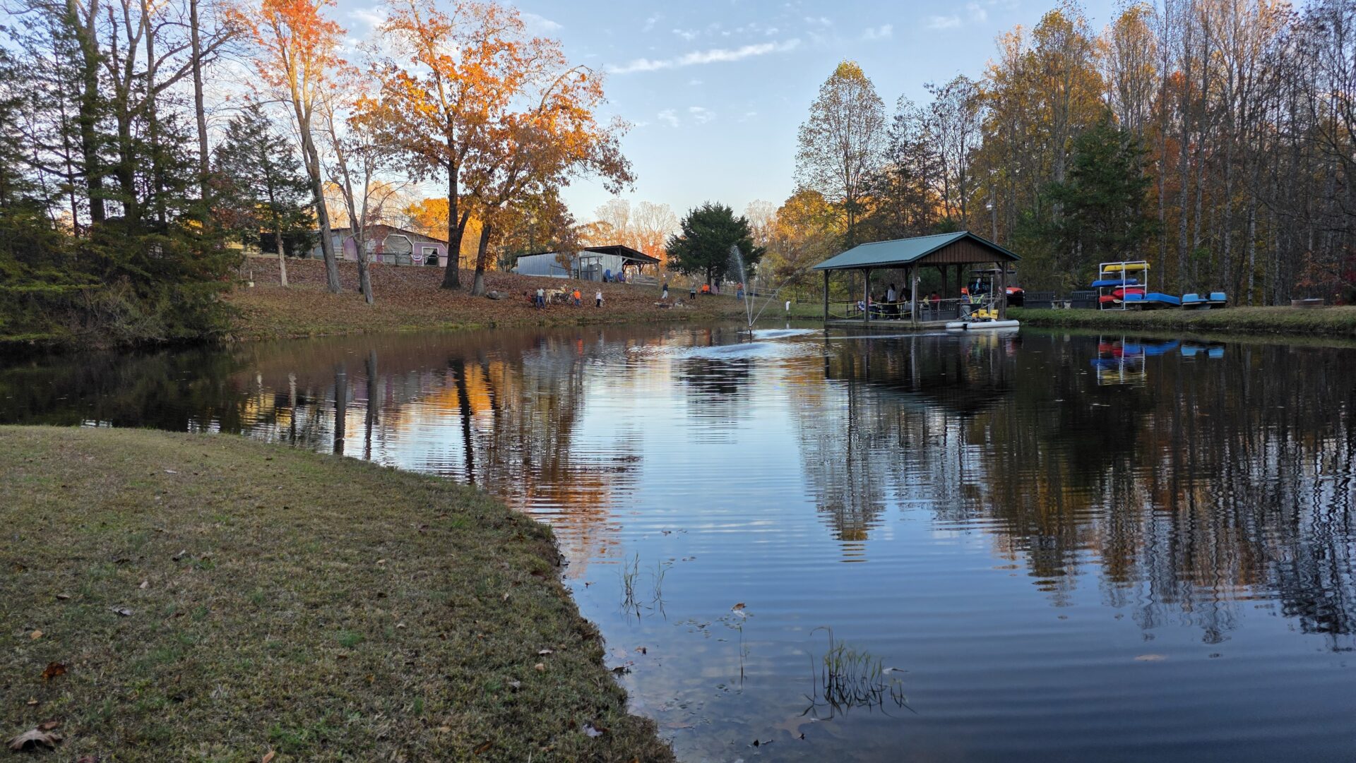 A peaceful lake reflecting autumn trees and a small dock.