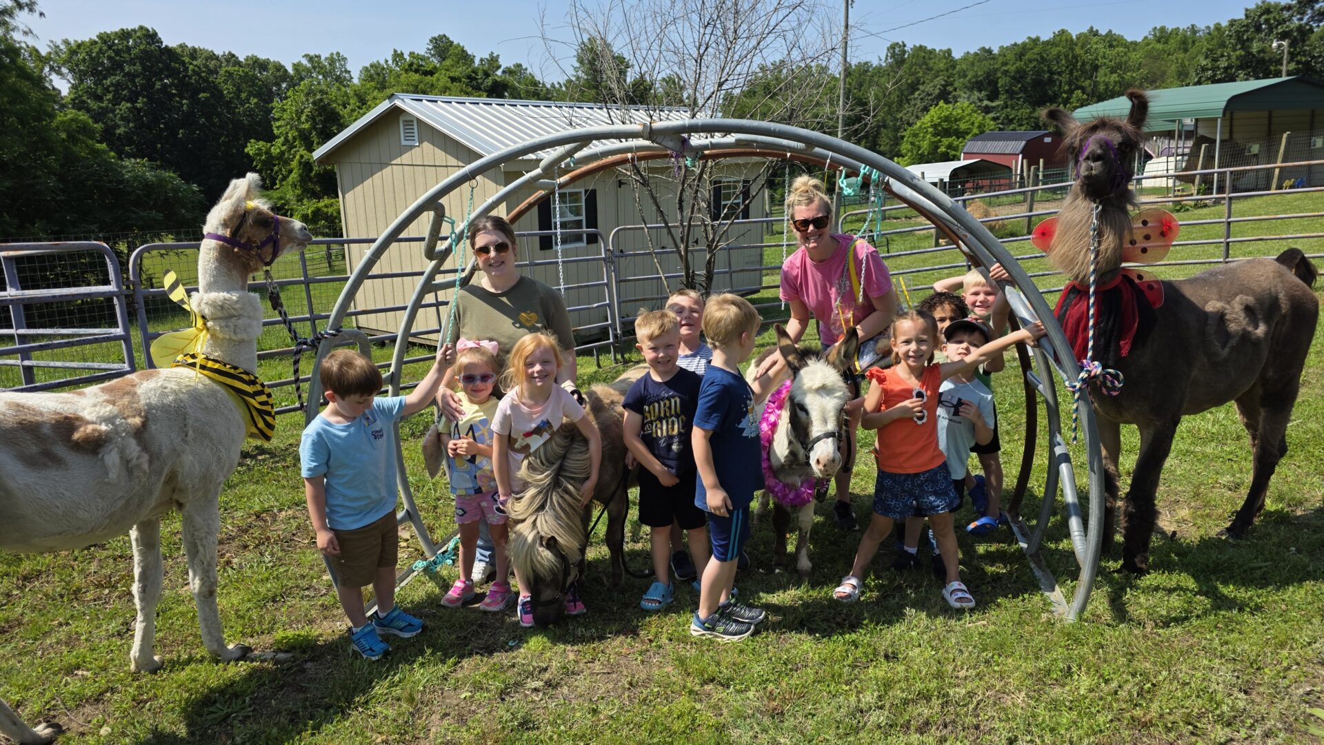Group of children and adults posing outdoors with a play structure.