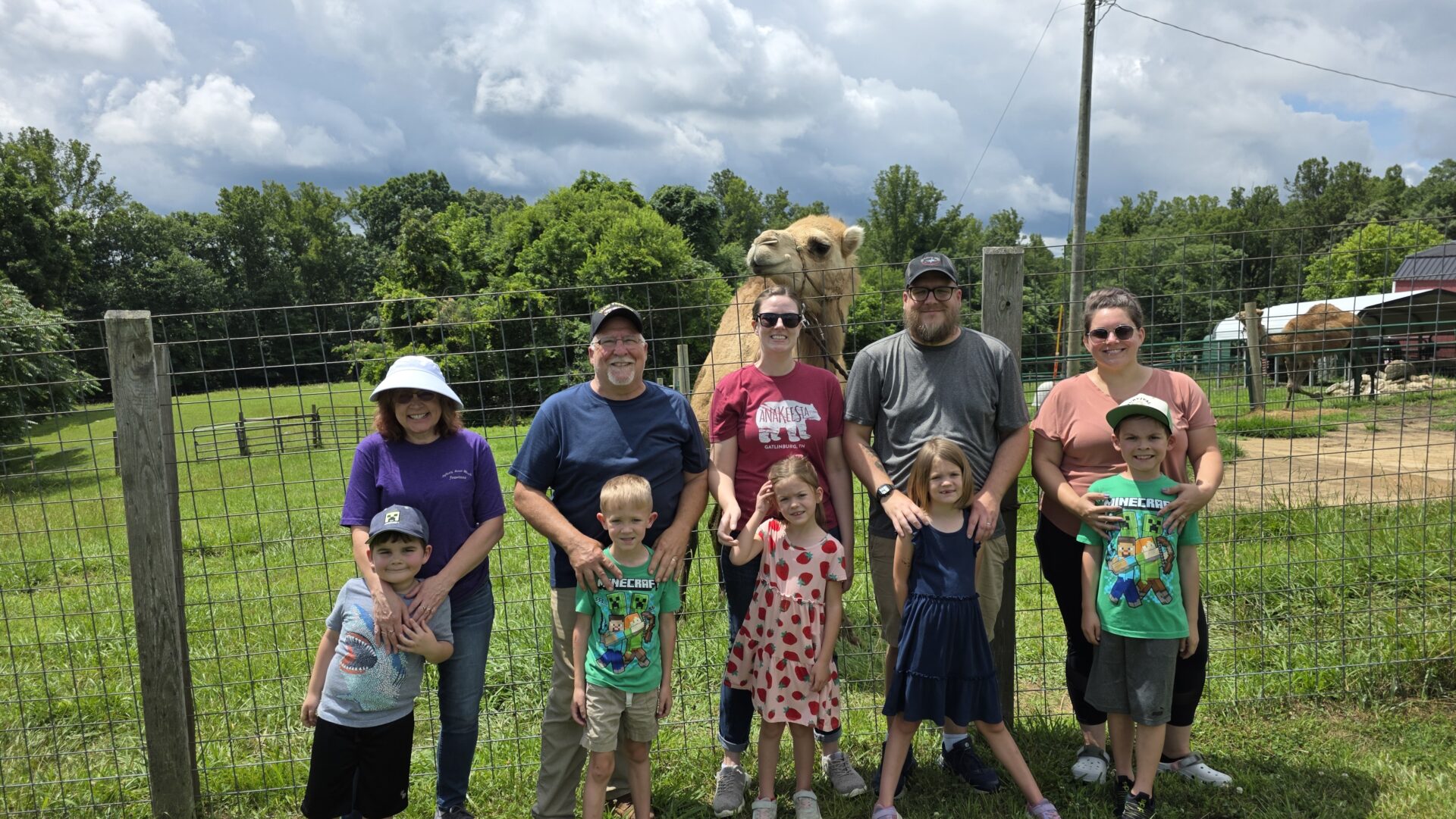 Family and friends posing outdoors on a cloudy day with a dog.