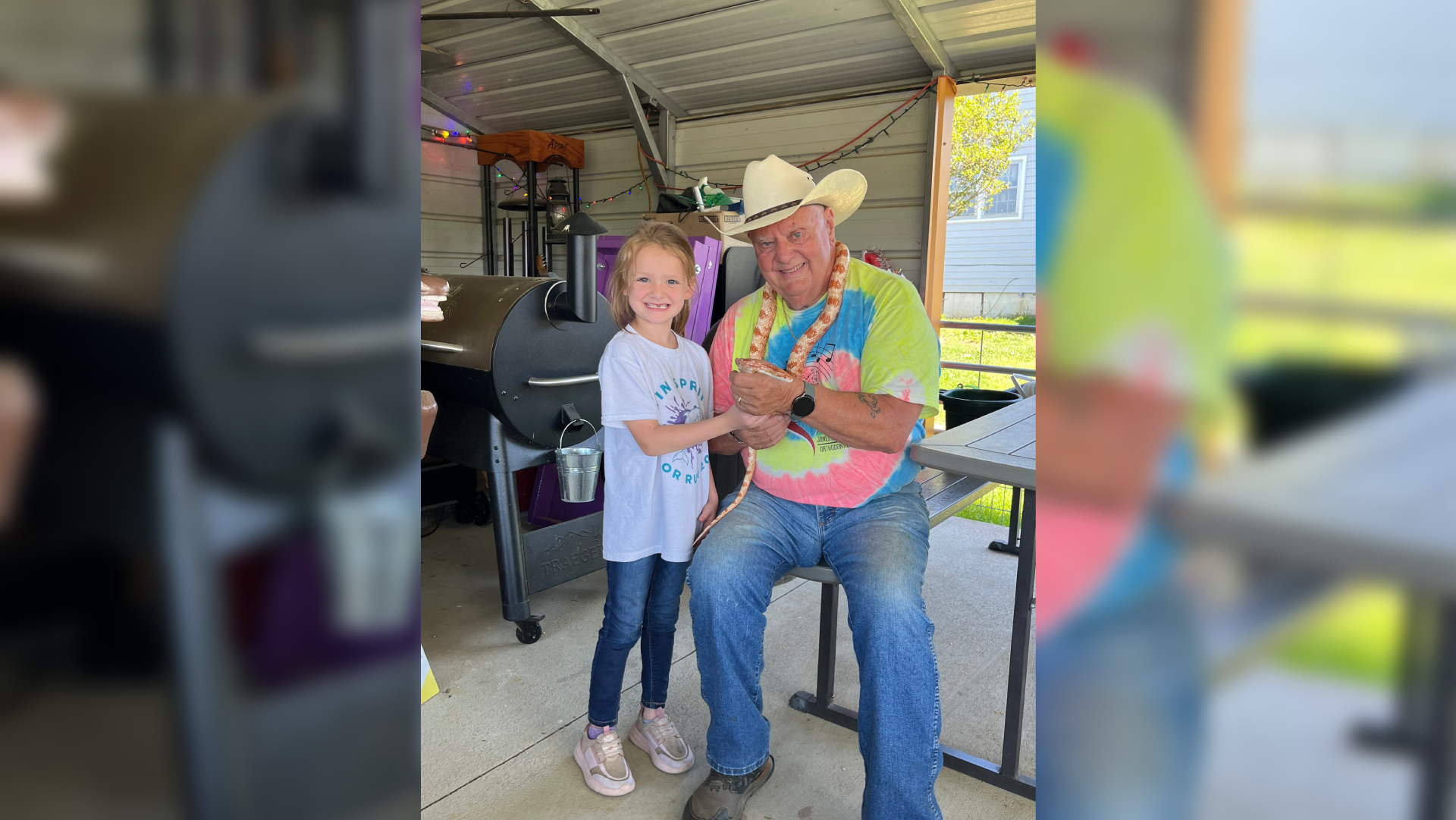 A man in a cowboy hat and a young girl share a joyful moment indoors.