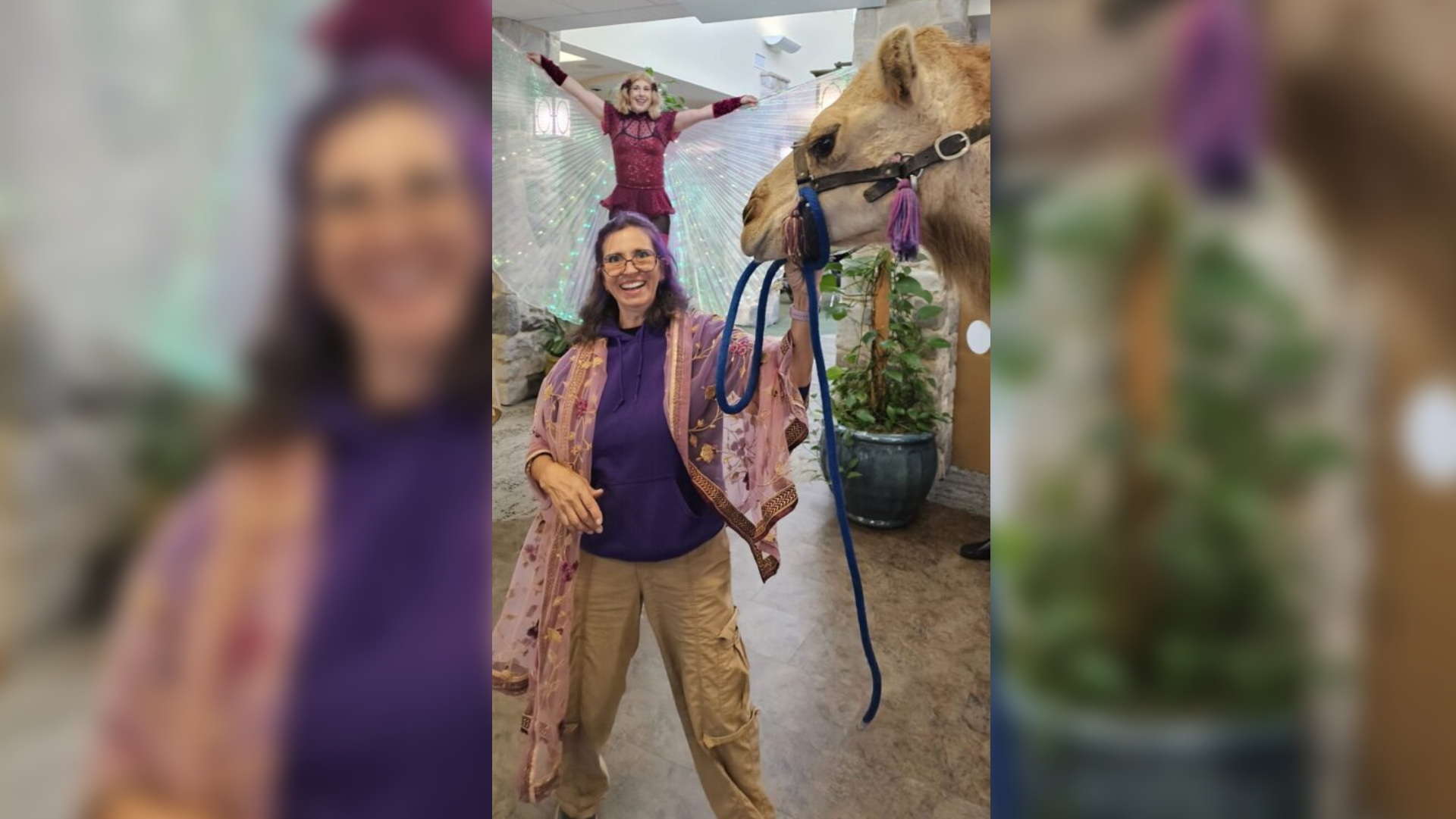 A person holding a leash and standing next to a camel.